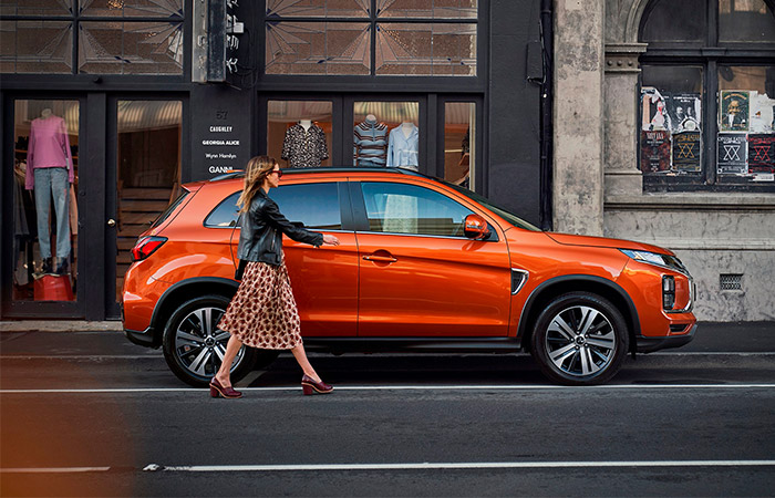 Side profile Orange ASX suv with woman walking to drivers side door