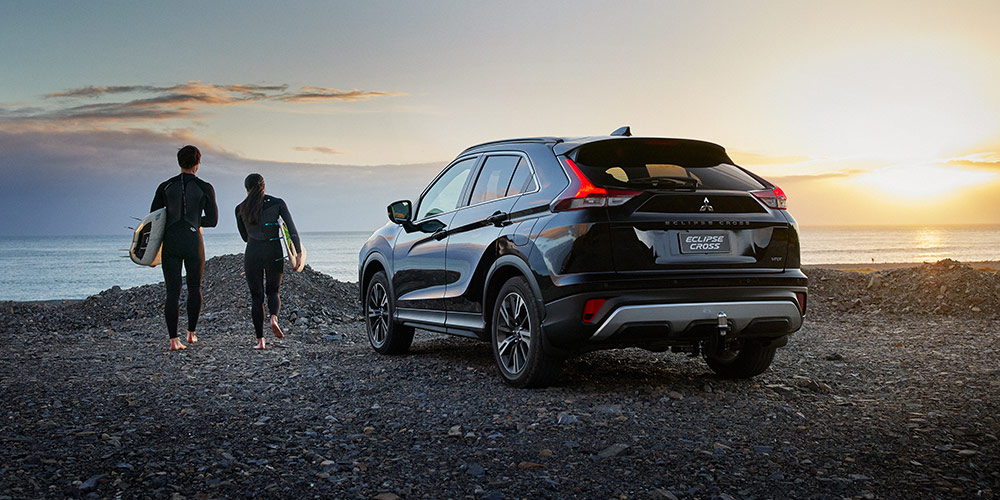 Black Eclipse cross on waterfront with surfers