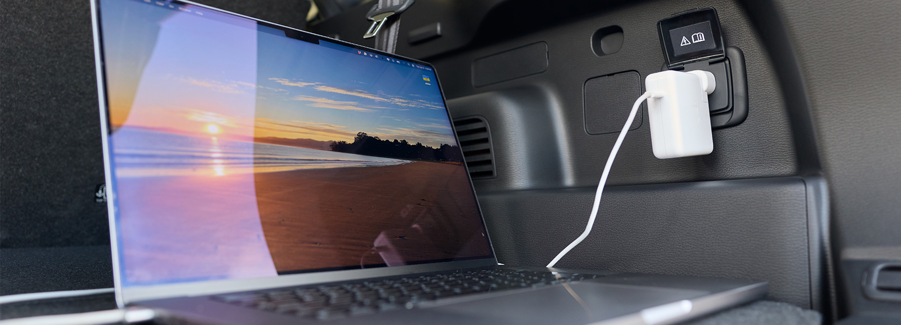 laptop plugged into the powerpoint in the rear of a Mitsubishi SUV