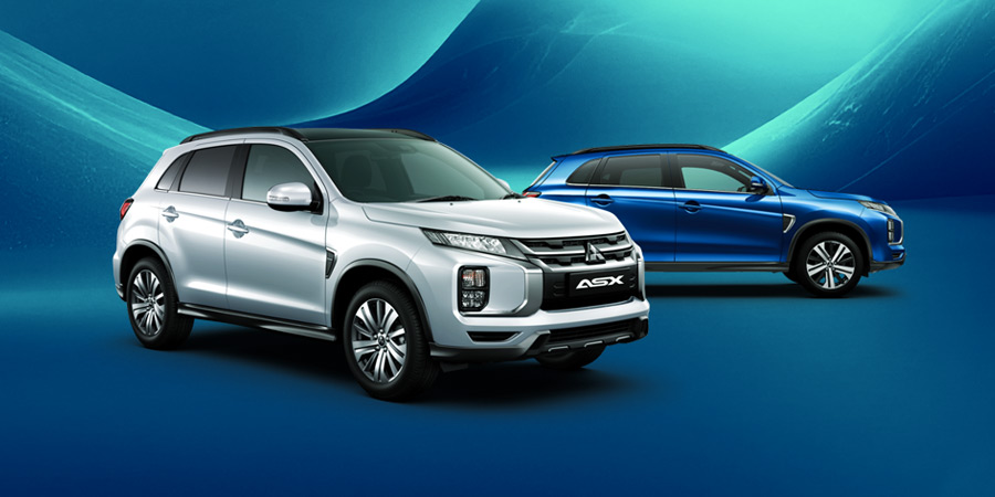 A small red Mitsubishi SUV parked in s a street, with a woman getting in the drivers side door