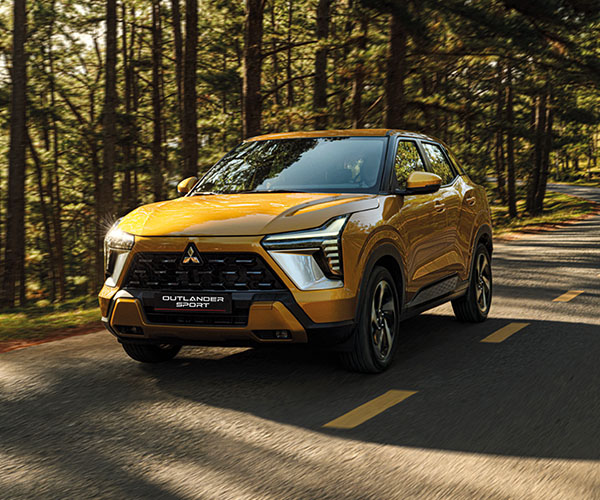 A yellow Outlander Sport driving on a forest road